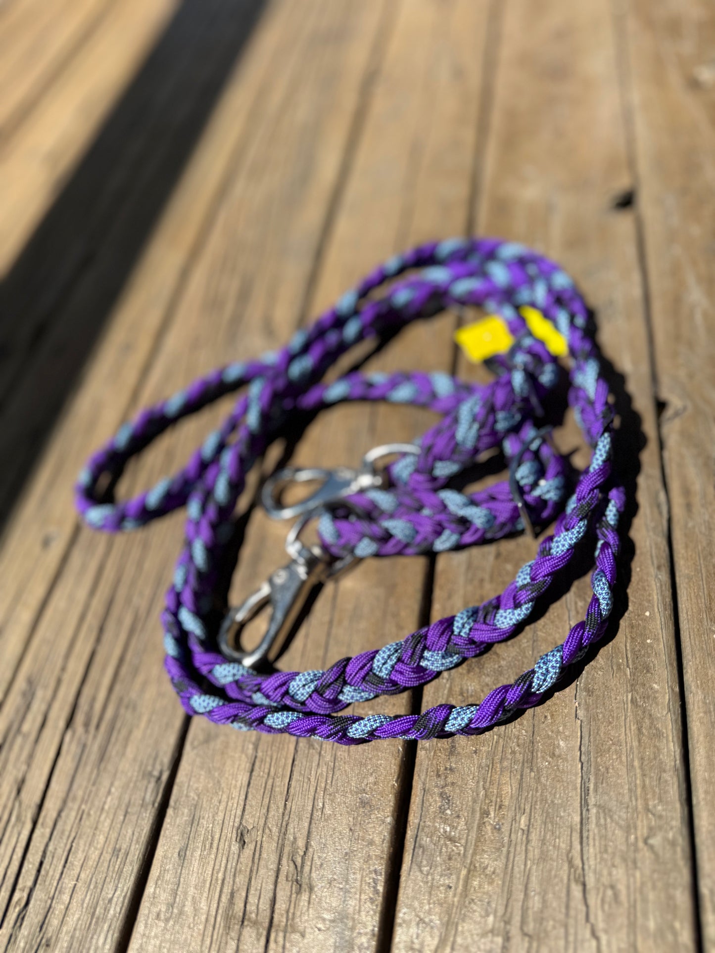 A set of flat braid barrel racing reins with no knots, featuring purple, black & lilac colours, with metal clasps on the end