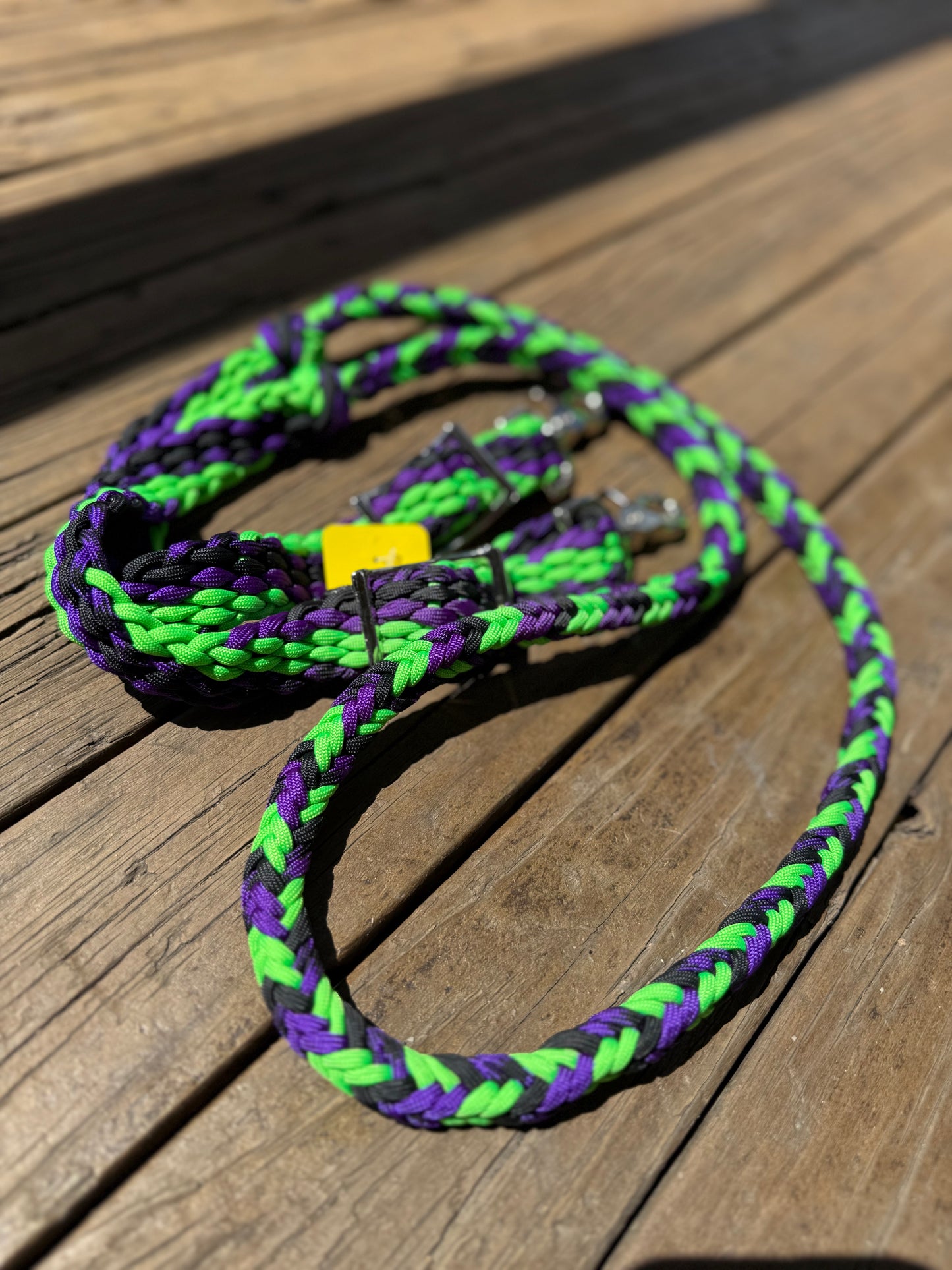Hand-braided barrel racing reins featuring neon purple, neon green, and black colorway