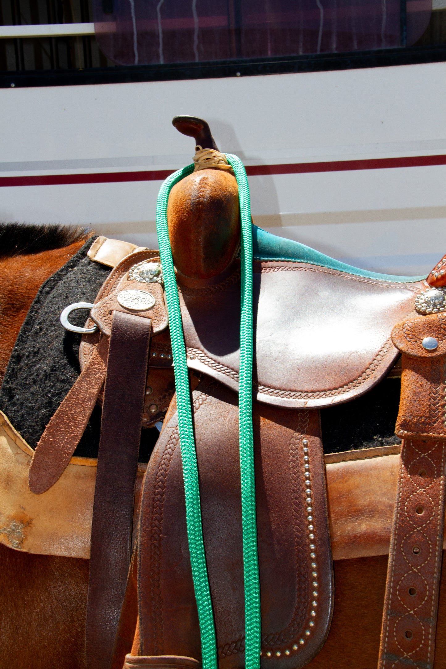 Brown leather saddle with a green rope on a blurred background