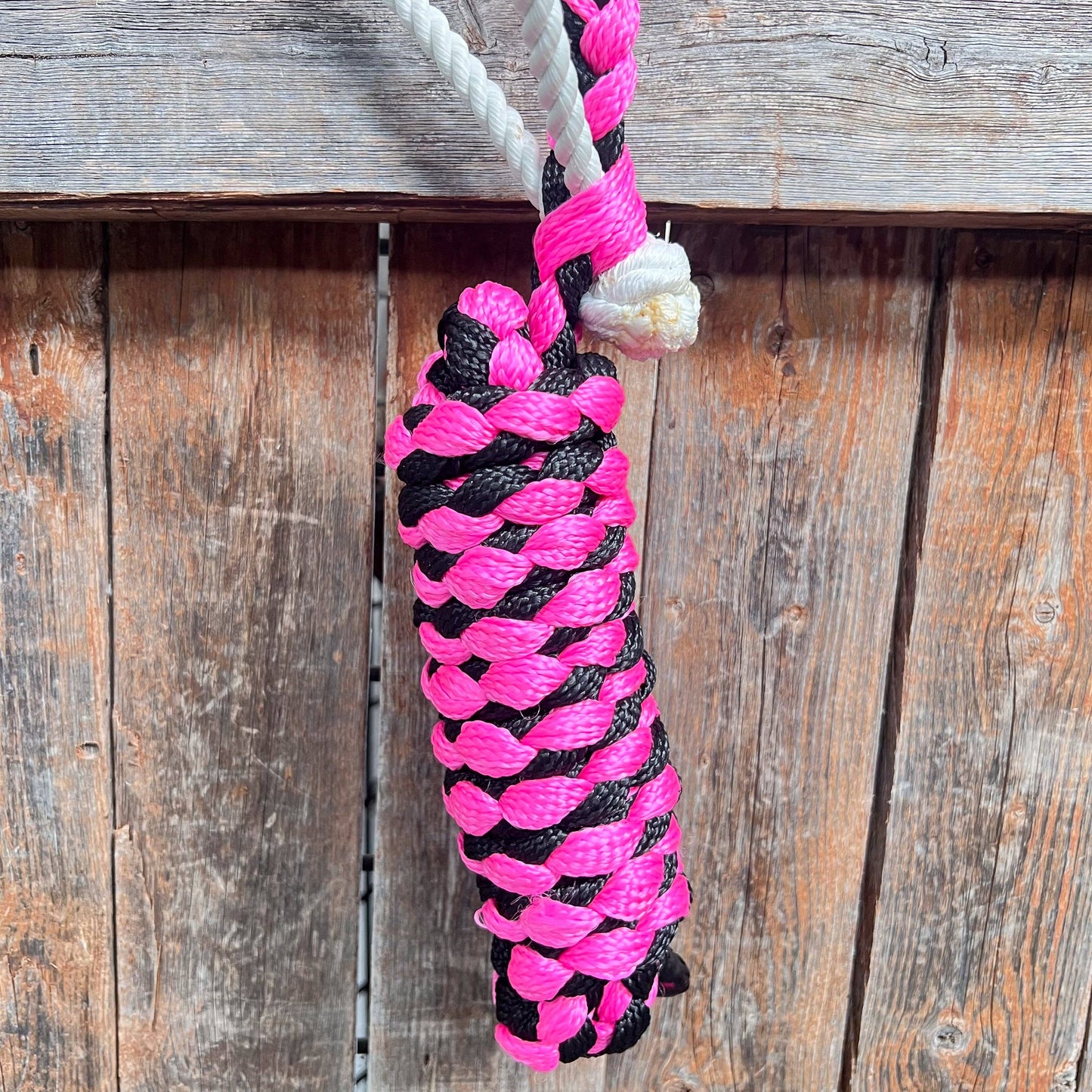 Pink and black braided rope against a wooden background