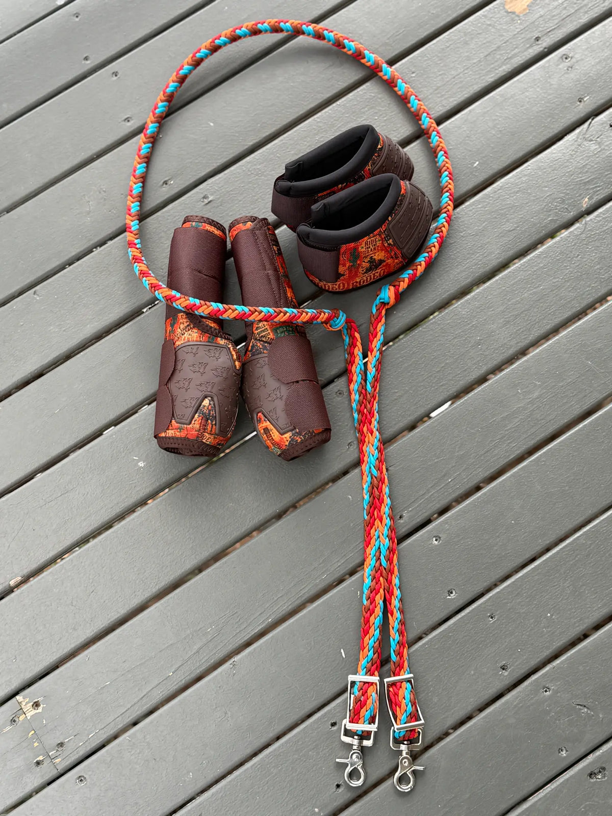 Full-length 8 Seconds colourway stabiliser reins with knots, buckles and trigger snaps beside matching horse boots and bell boots