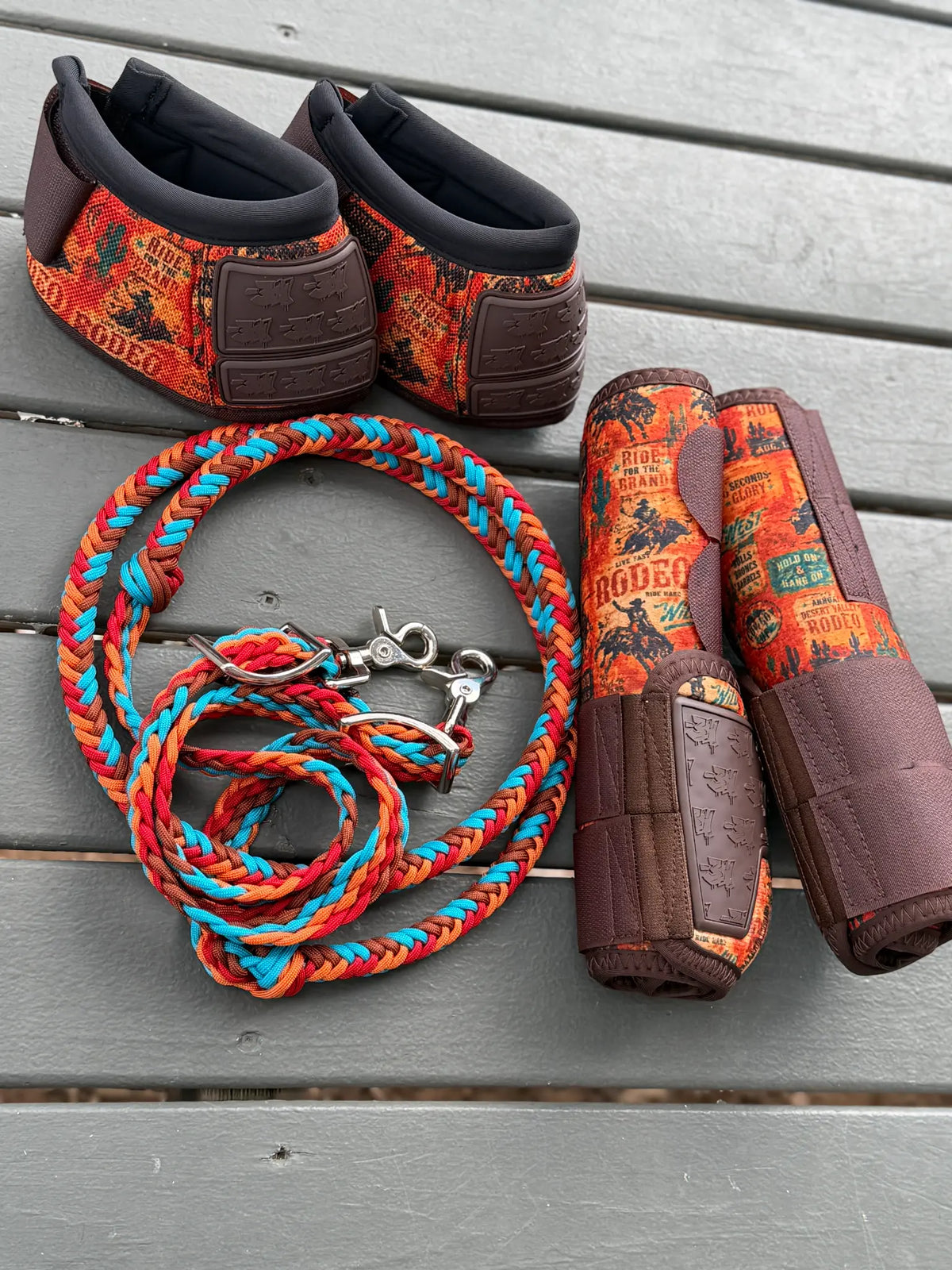 Rust brown, red, orange and turquoise stabiliser reins alongside matching 8 Seconds horse boots and bell boots