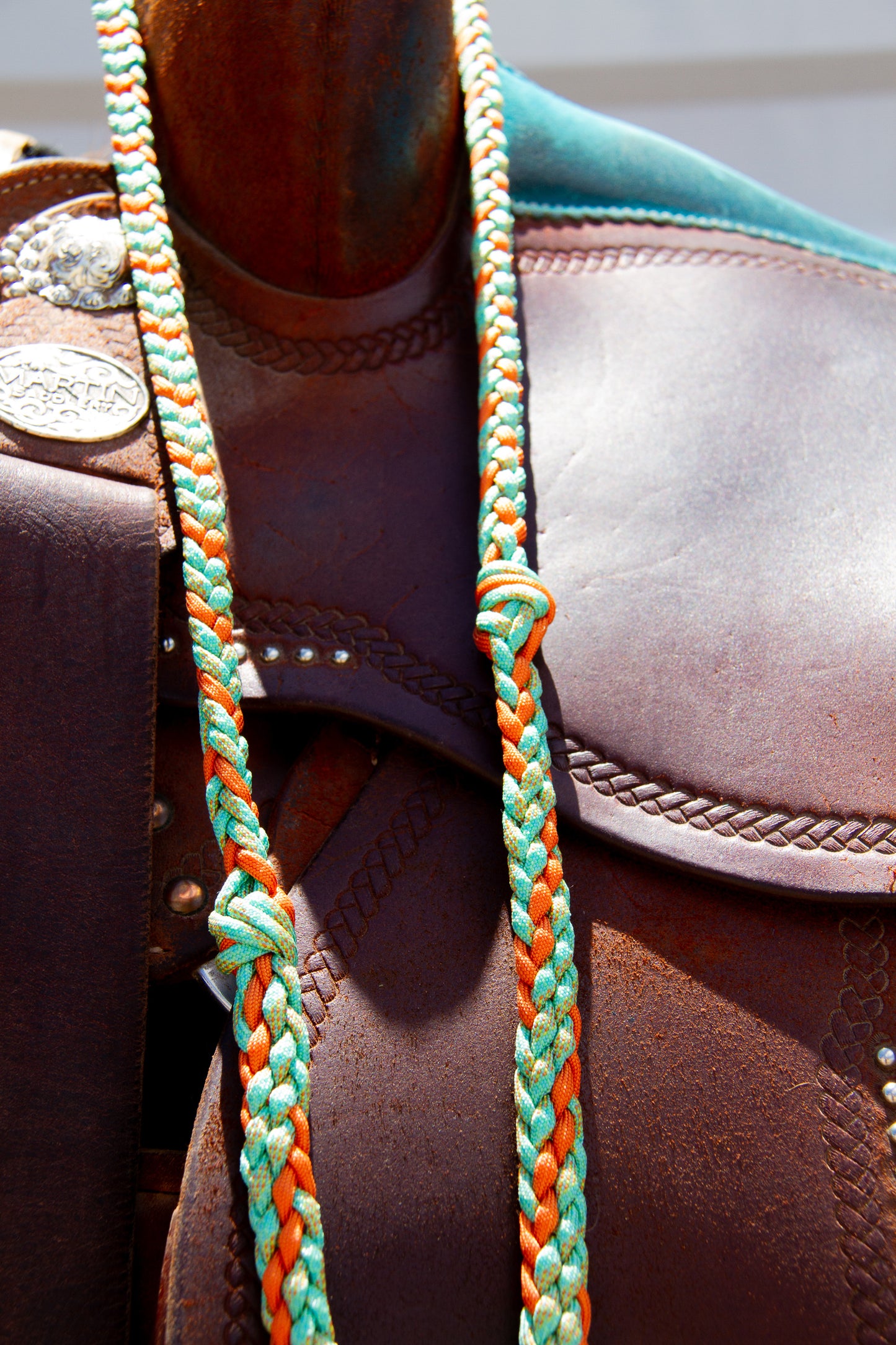 Close-up of a brown leather boot with a braided Turquoise and orange braided reins