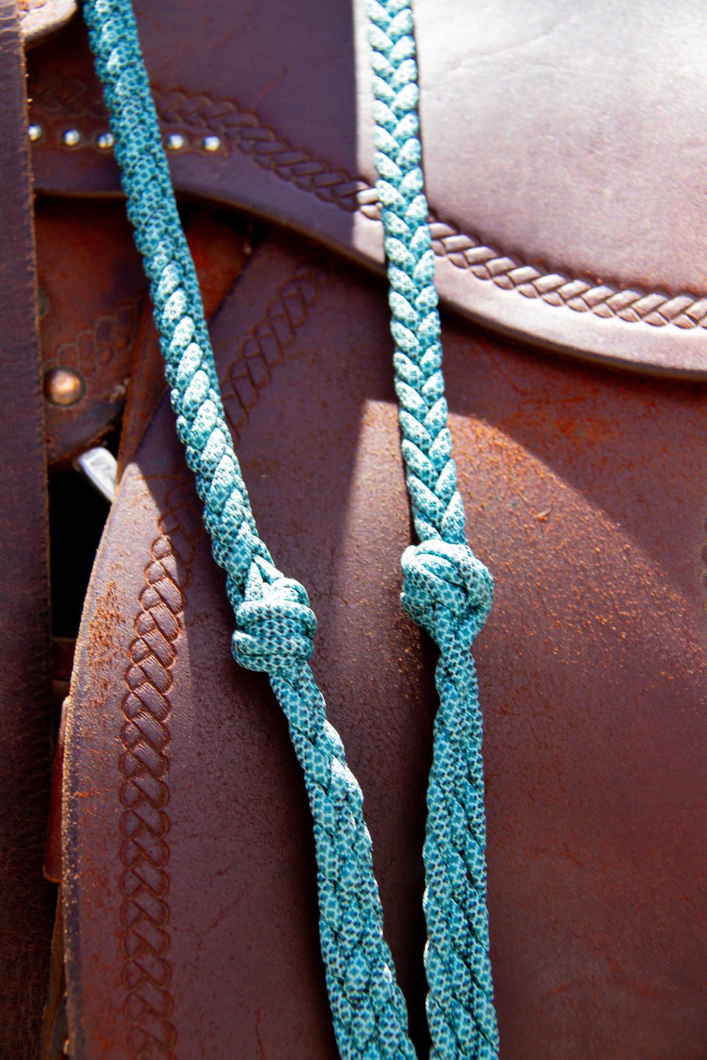 Teal braided reins on a brown leather horse saddle