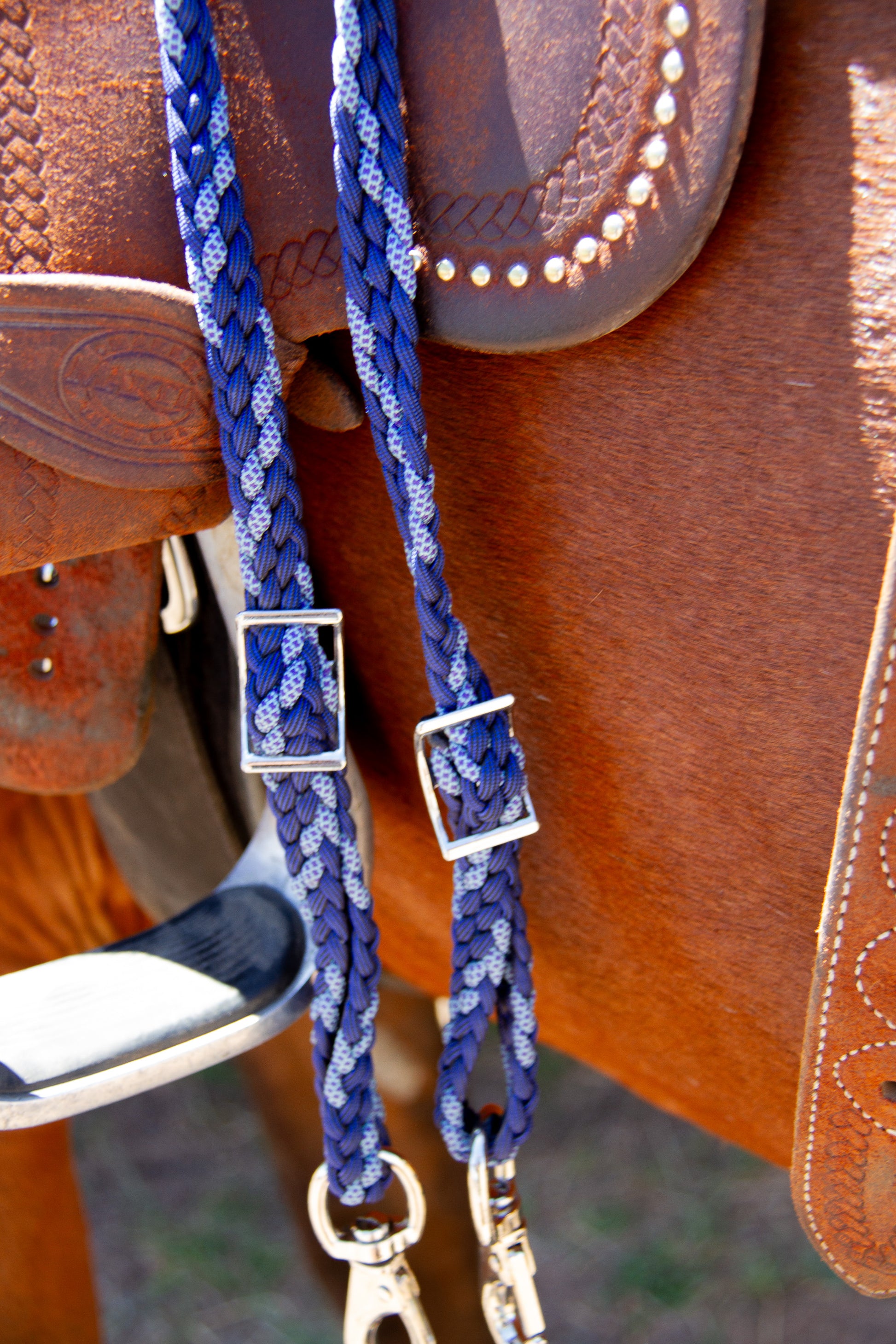 Close-up of a blue braided horse bridle on a brown leather saddle.