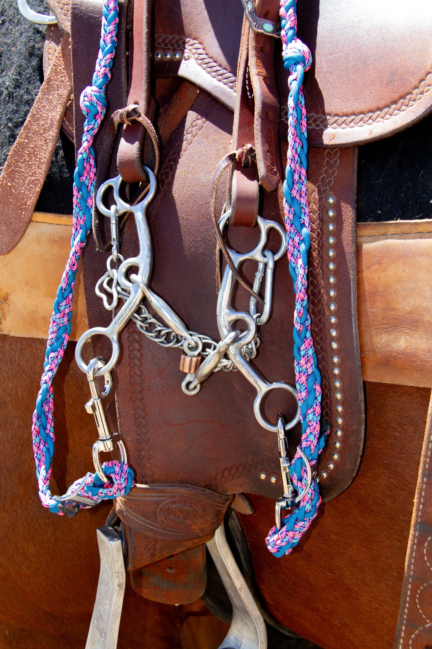 Horse bridle with colorful reins on a brown leather saddle