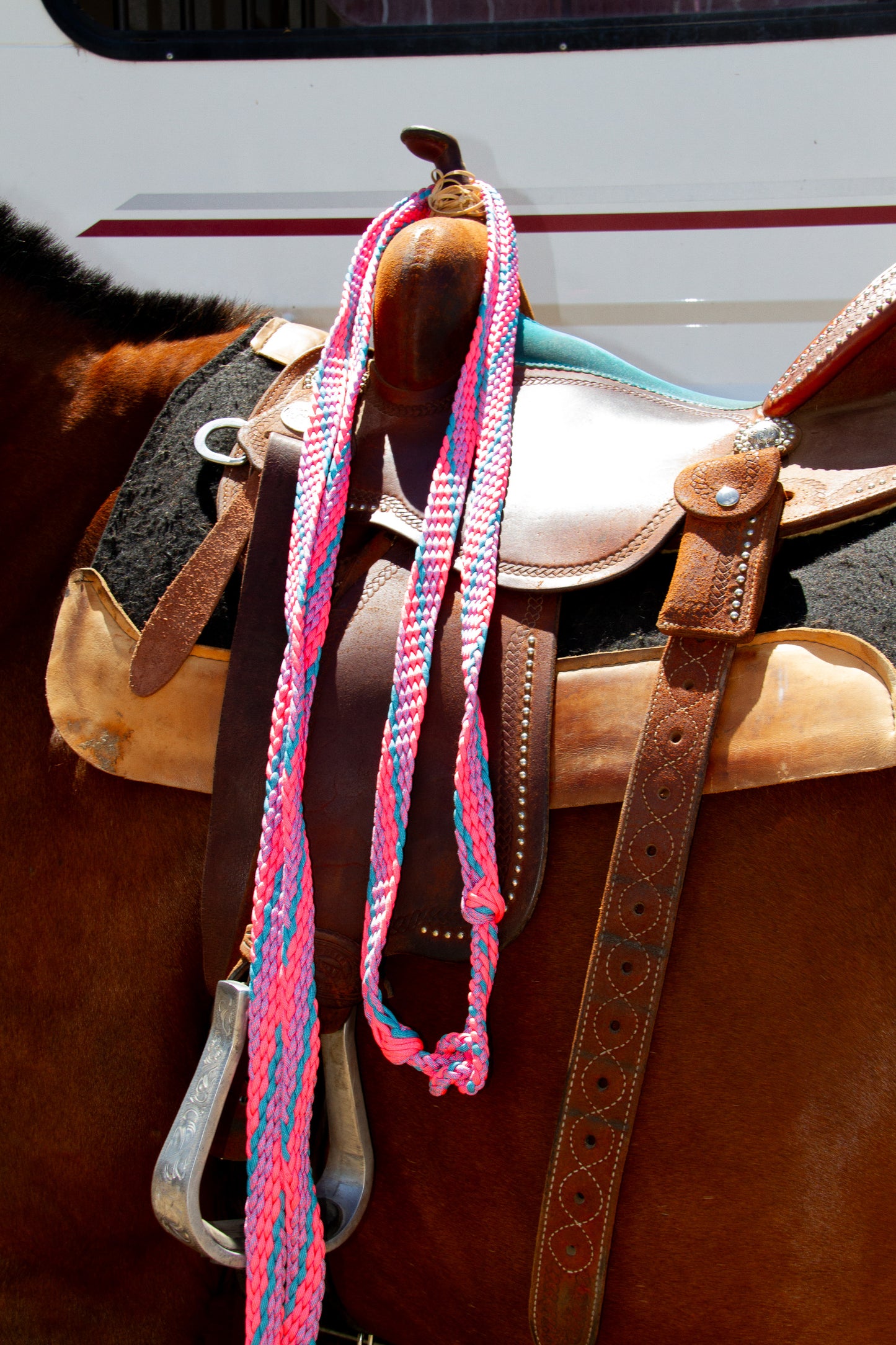 Close-up of a horse saddle with pink and blue reins on a blurred background