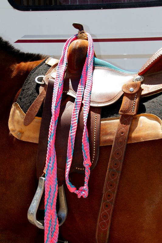 Close-up of a horse saddle with pink and blue reins on a blurred background