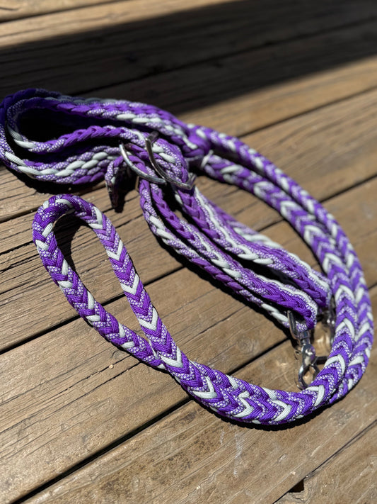Purple and silver 6 strand braided reins with Conway buckles and trigger snaps, laid on timber boards in sunlight.