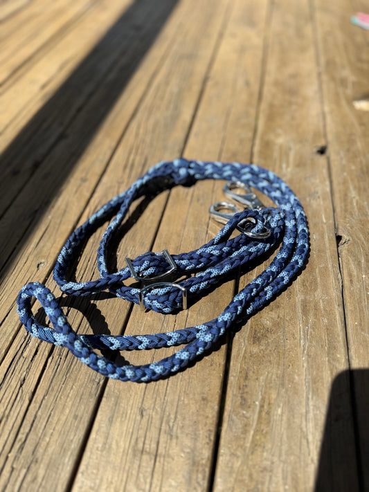Roping reins in royal blue and mixed blue pattern nylon, laid on timber boards with stainless Conway buckles and trigger snaps.