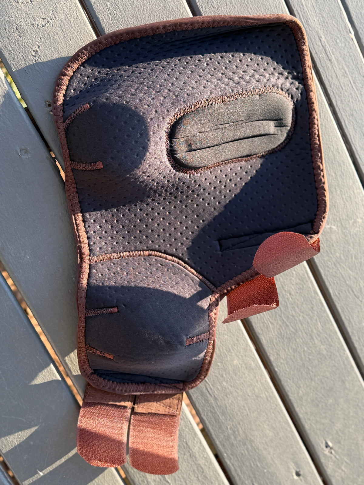 8 Seconds sport boot laid open to show perforated lining, shaped inner pad, brown edging and fastening straps.