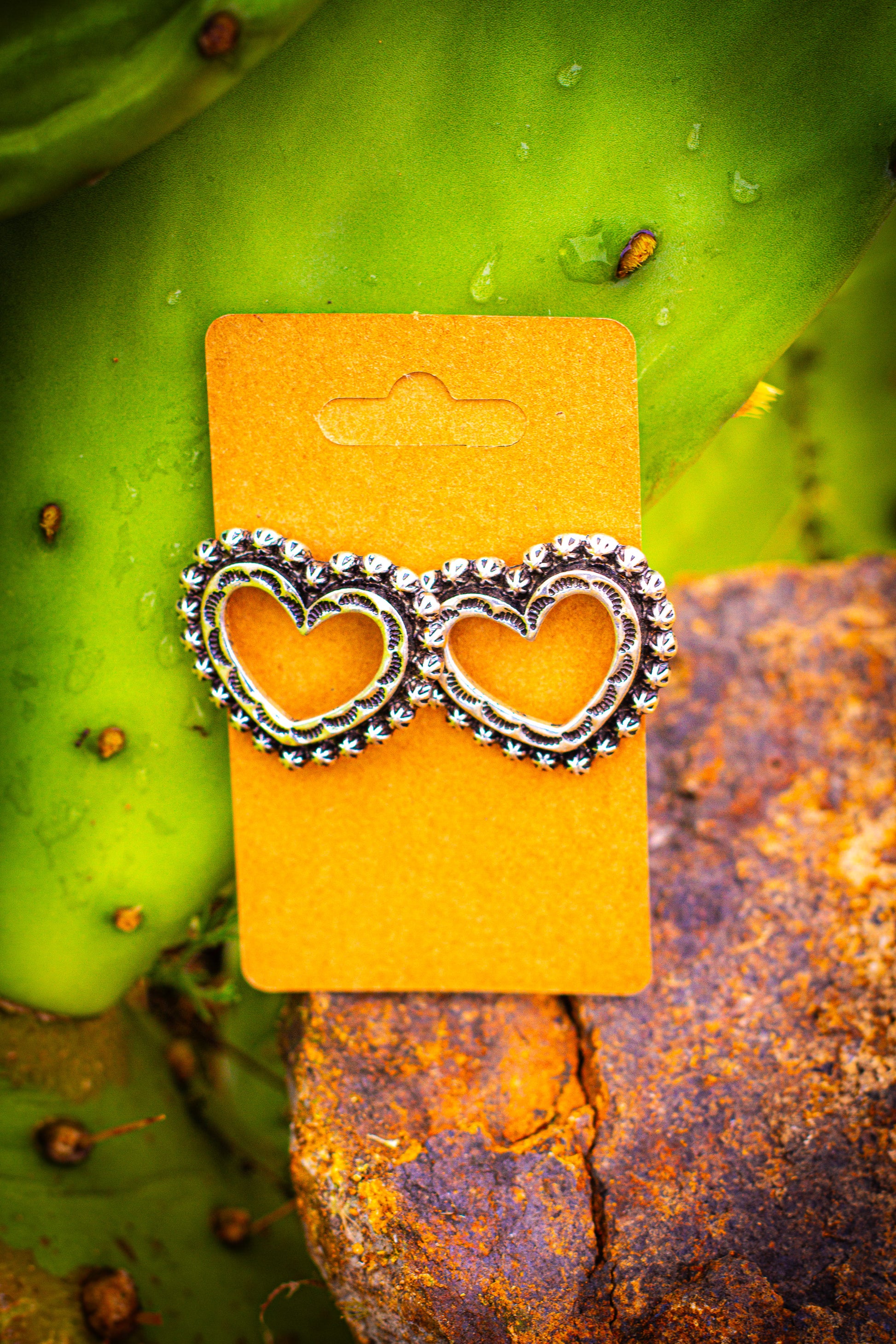 Heart-shaped earrings on a yellow card against a natural background