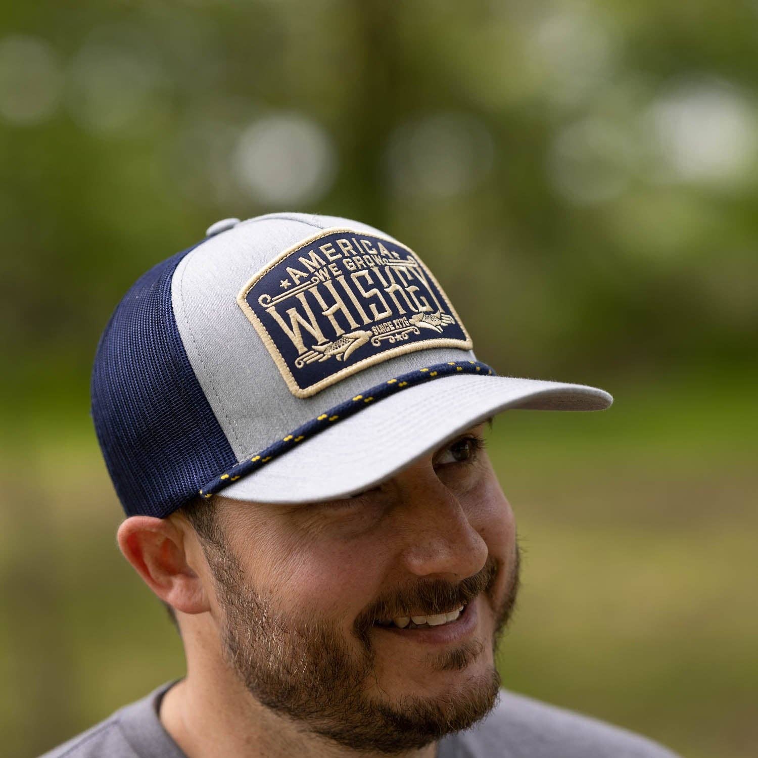 Man wearing a cap with 'America's Finest Whiskey' branding outdoors.