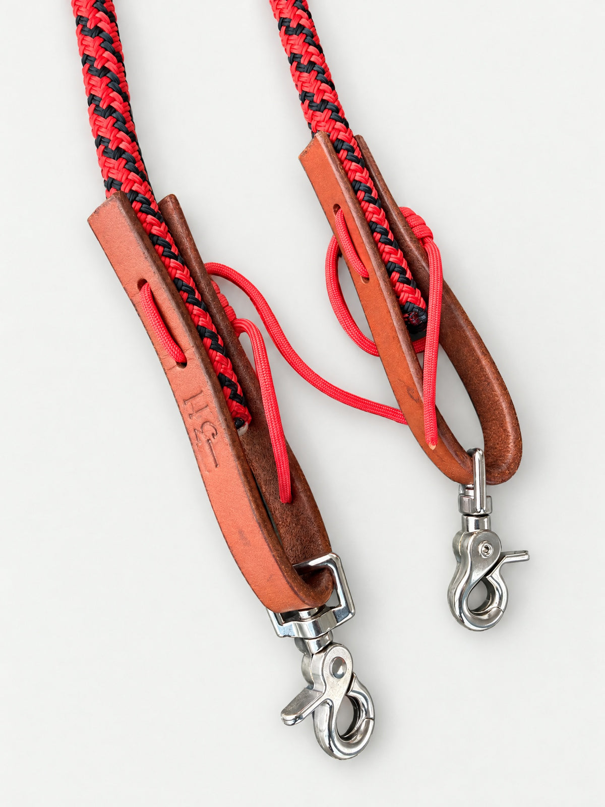 Close-up of leather keepers, red and black rope and trigger snaps on joined reins