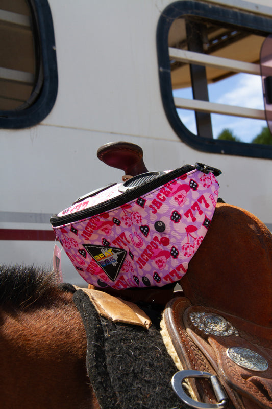 Pink patterned bag on a horse's back with a trailer in the background