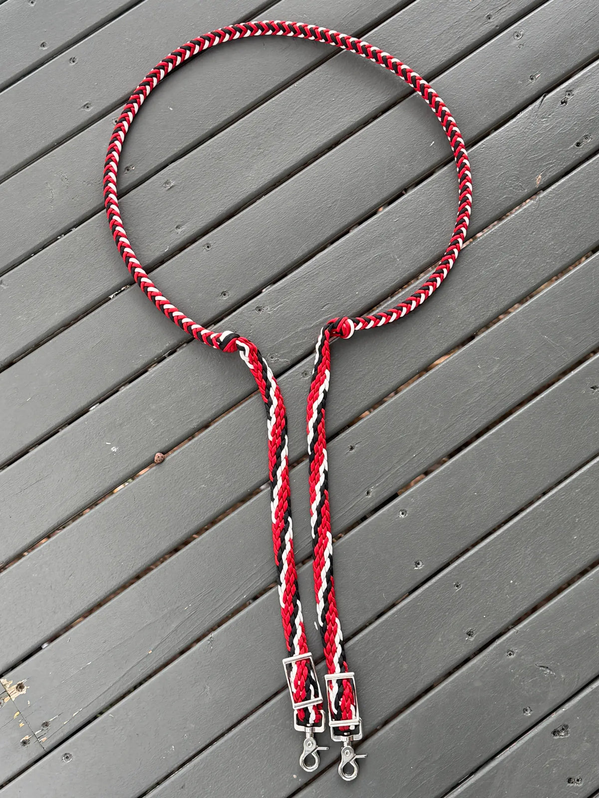 Full-length black, white and red stabiliser reins laid out on timber decking with buckles and trigger snaps