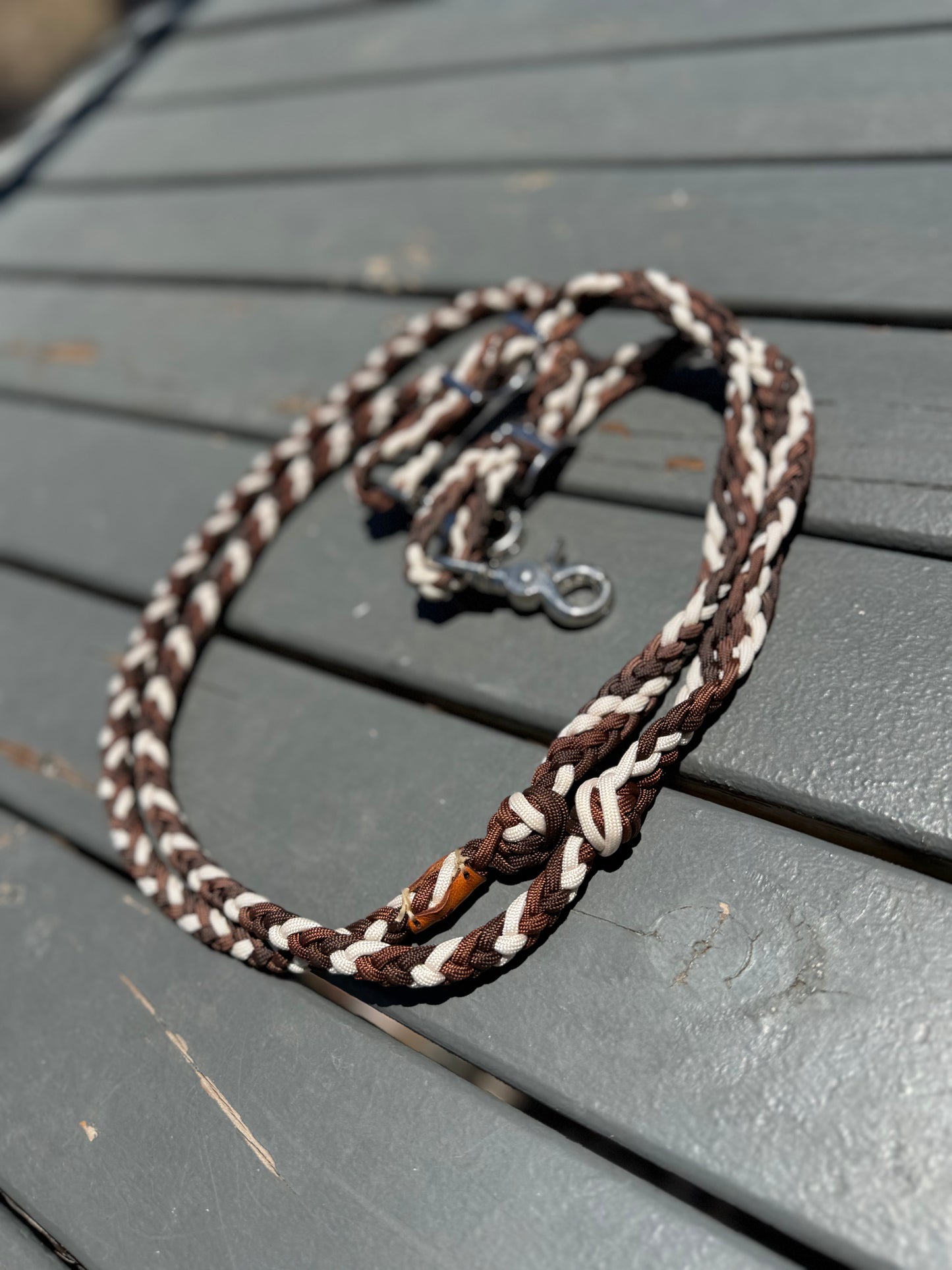 Brown and white braided reins on a gray wooden surface