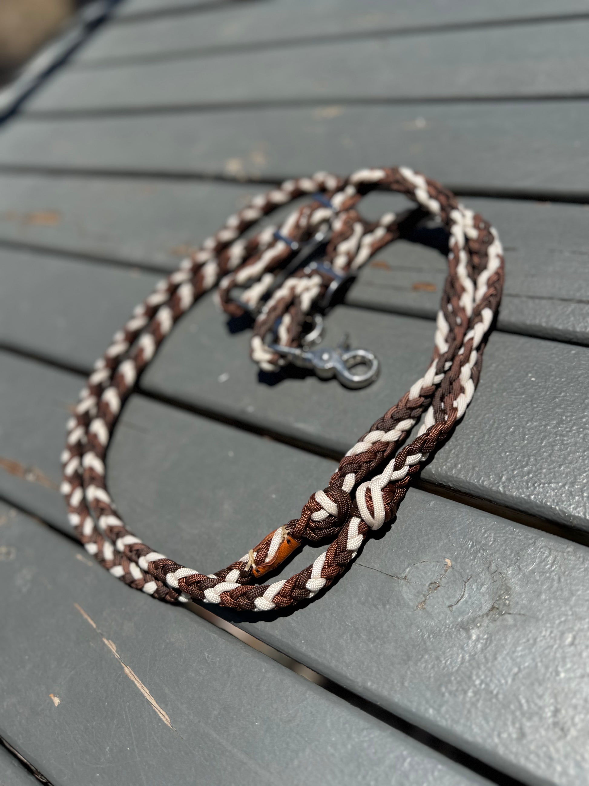 Brown and white braided reins on a gray wooden surface