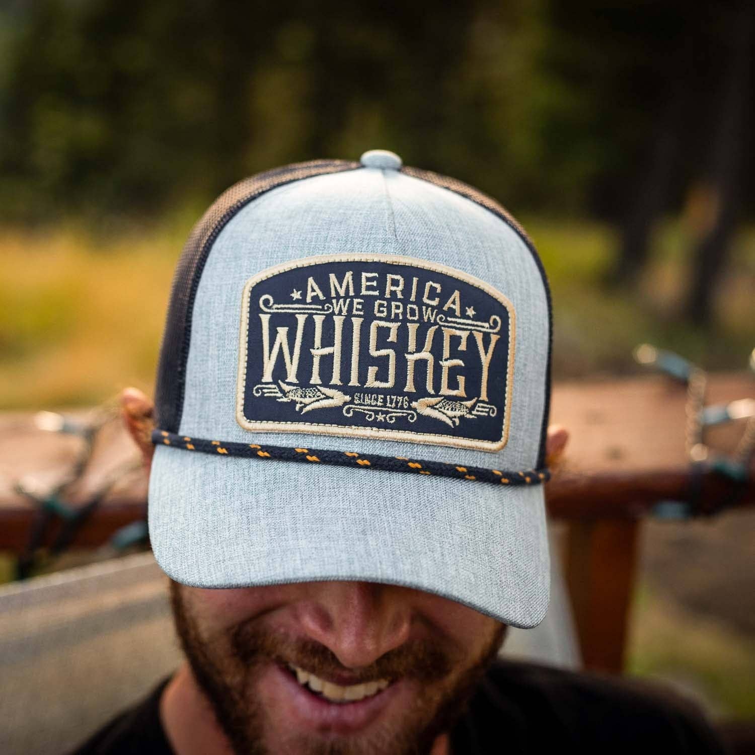 Person wearing a cap with 'America We Grow Whiskey' text in an outdoor setting
