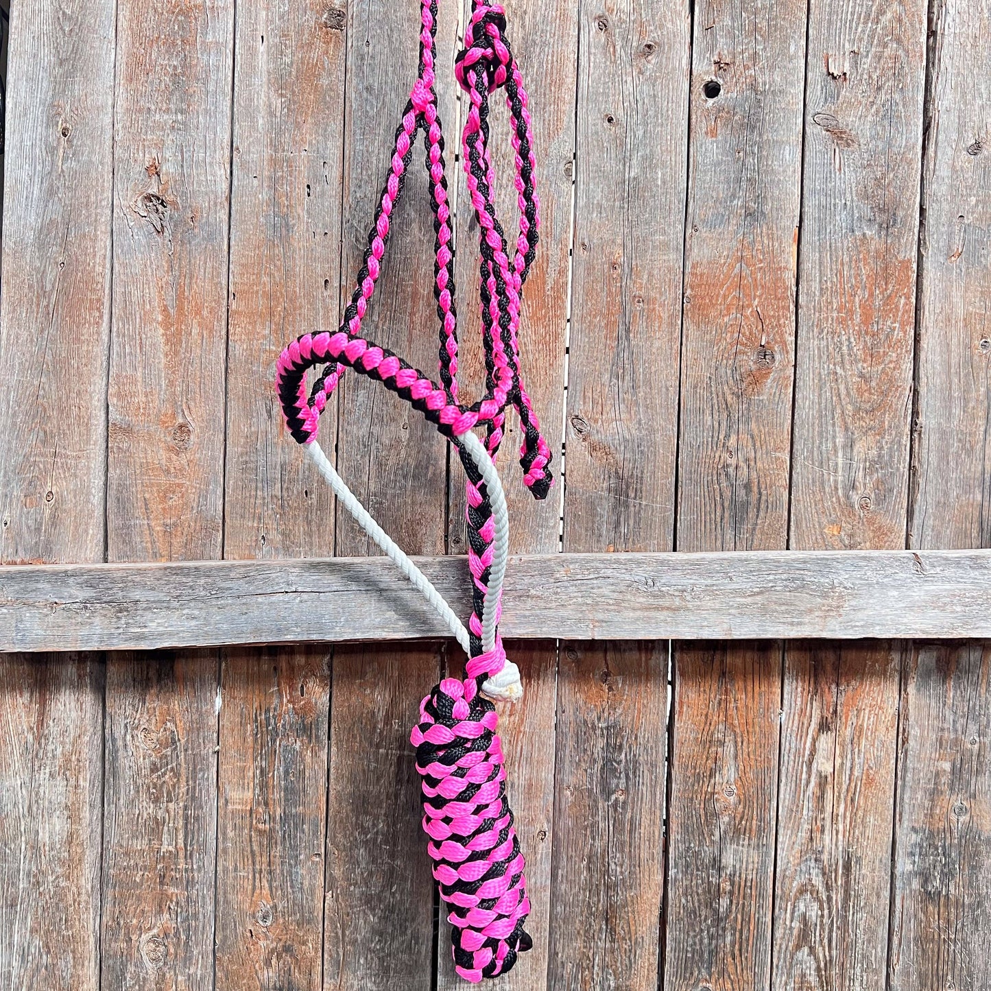 Pink and black braided rope against a wooden background