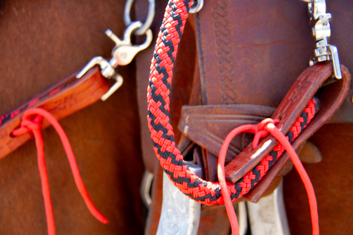 Close-up of a horse bridle with red and black reins on a brown leather background