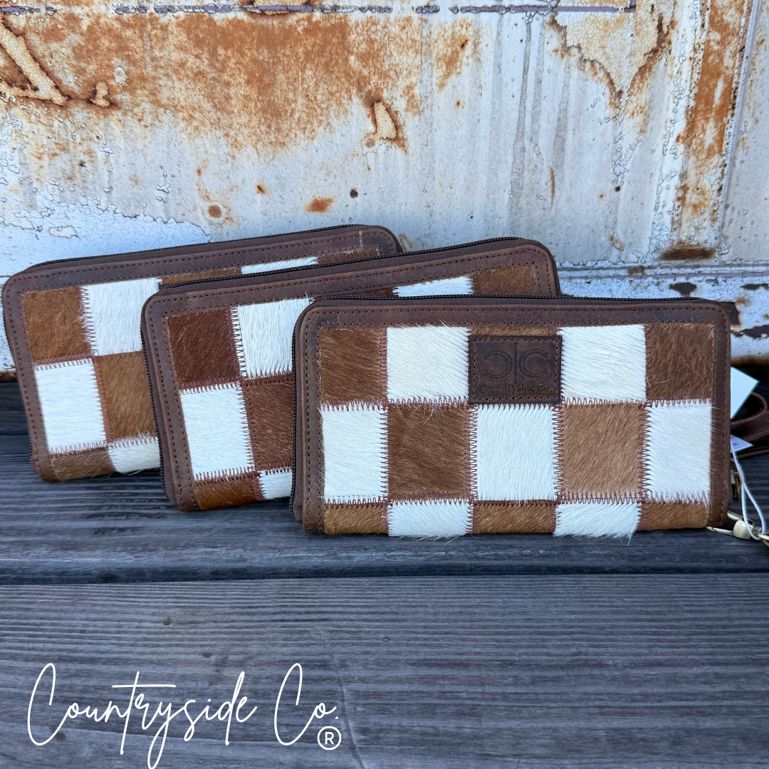 Three checkered wallets on a rustic wooden surface with a metal background, featuring the 'Countryside Co' brand.