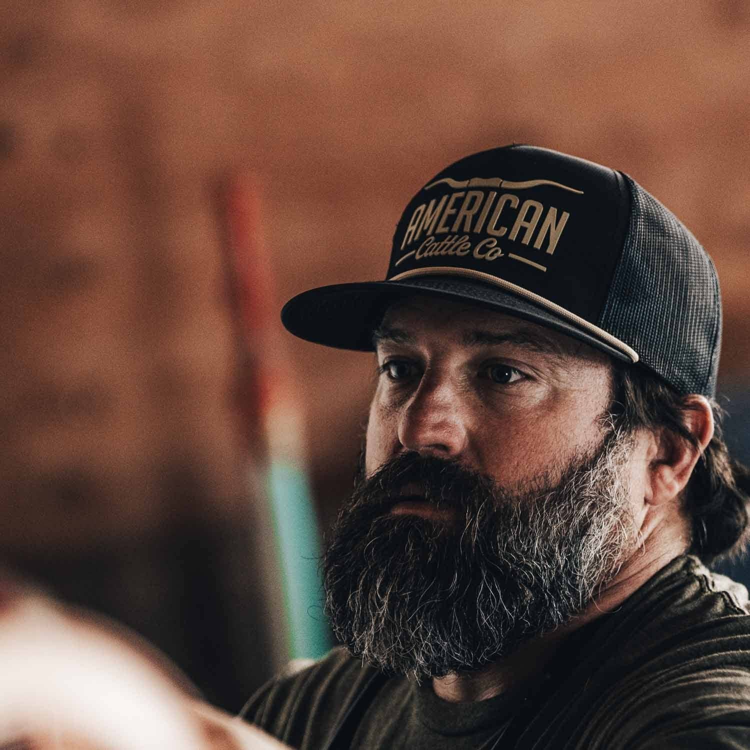 Man wearing an 'American Lumber Co.' cap with a blurred background