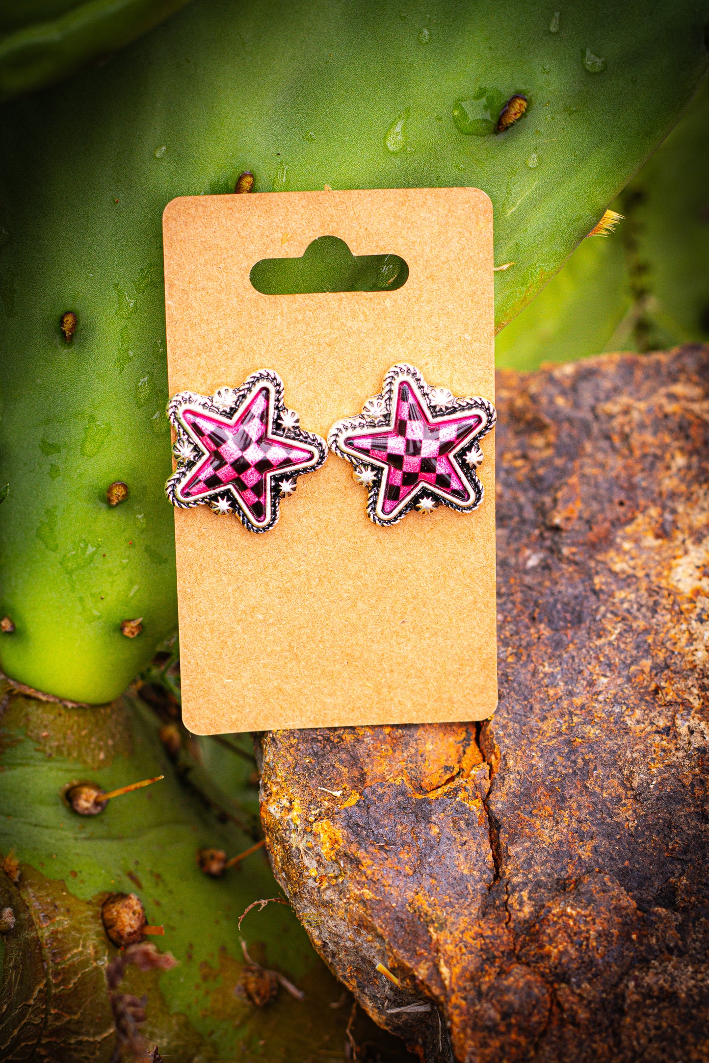 Star-shaped earrings on a cardboard backing with a cactus background