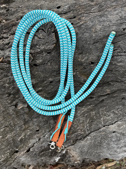Turquoise-and-white 12mm rope split reins with tan leather keepers and trigger snaps, coiled on timber